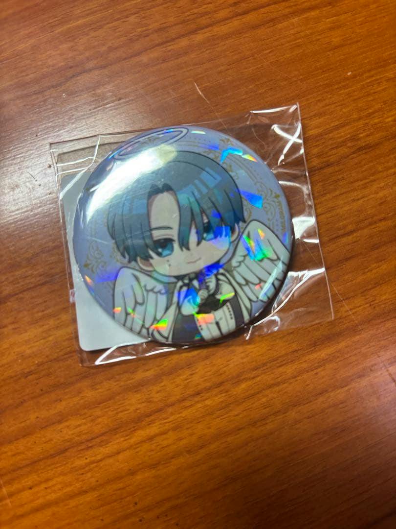 Sealed holographic can badge of the Angel character "シドウ" (Shidou) in plastic packaging on a wooden surface.