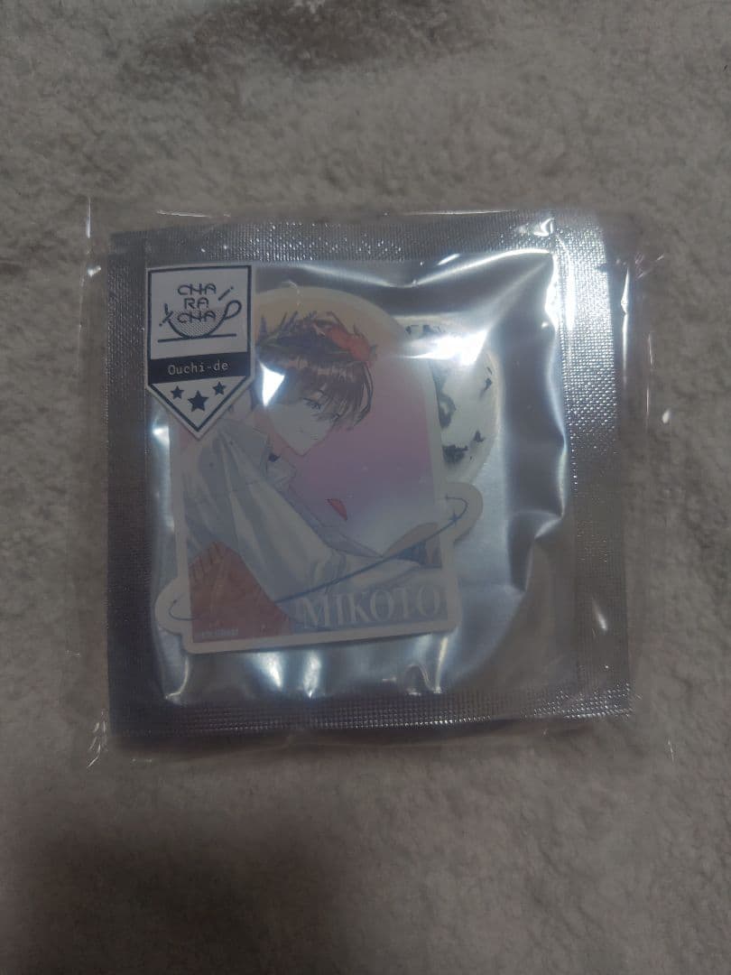 Front view of a sealed foil pouch black tea bag with a character sticker labeled "MIKOTO" on a fabric background.