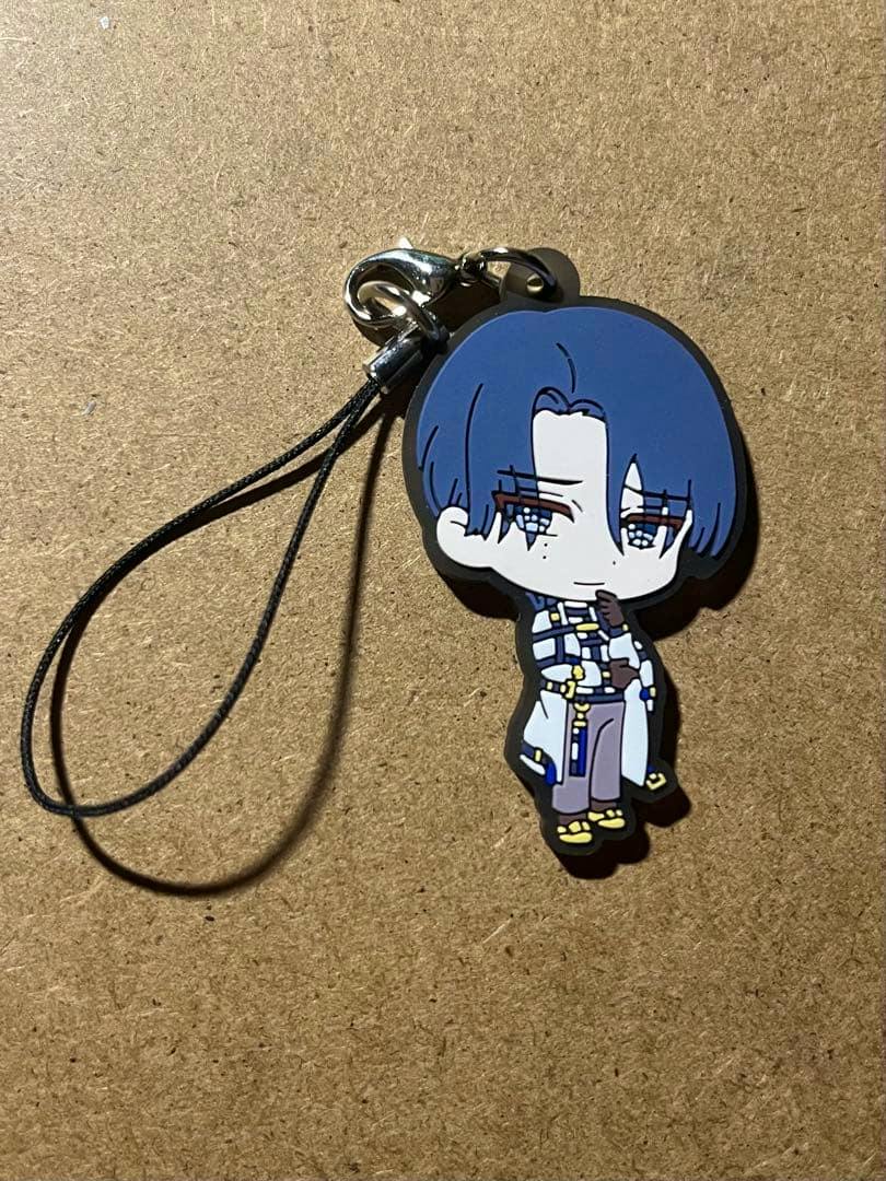 Photo of a rubber keychain strap showing a chibi blue‑haired character on a brown surface.