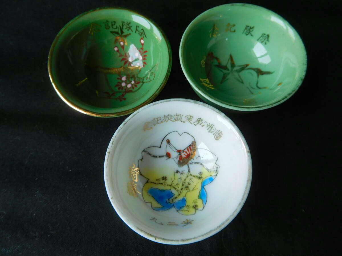 Three small ceramic sake cups shown from above: two green cups and one white cup with decorative painted designs.