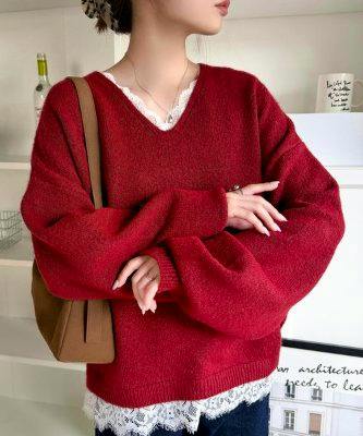Model wearing a red V-neck sweater with white lace hem detail, shown from mid-torso to chin.