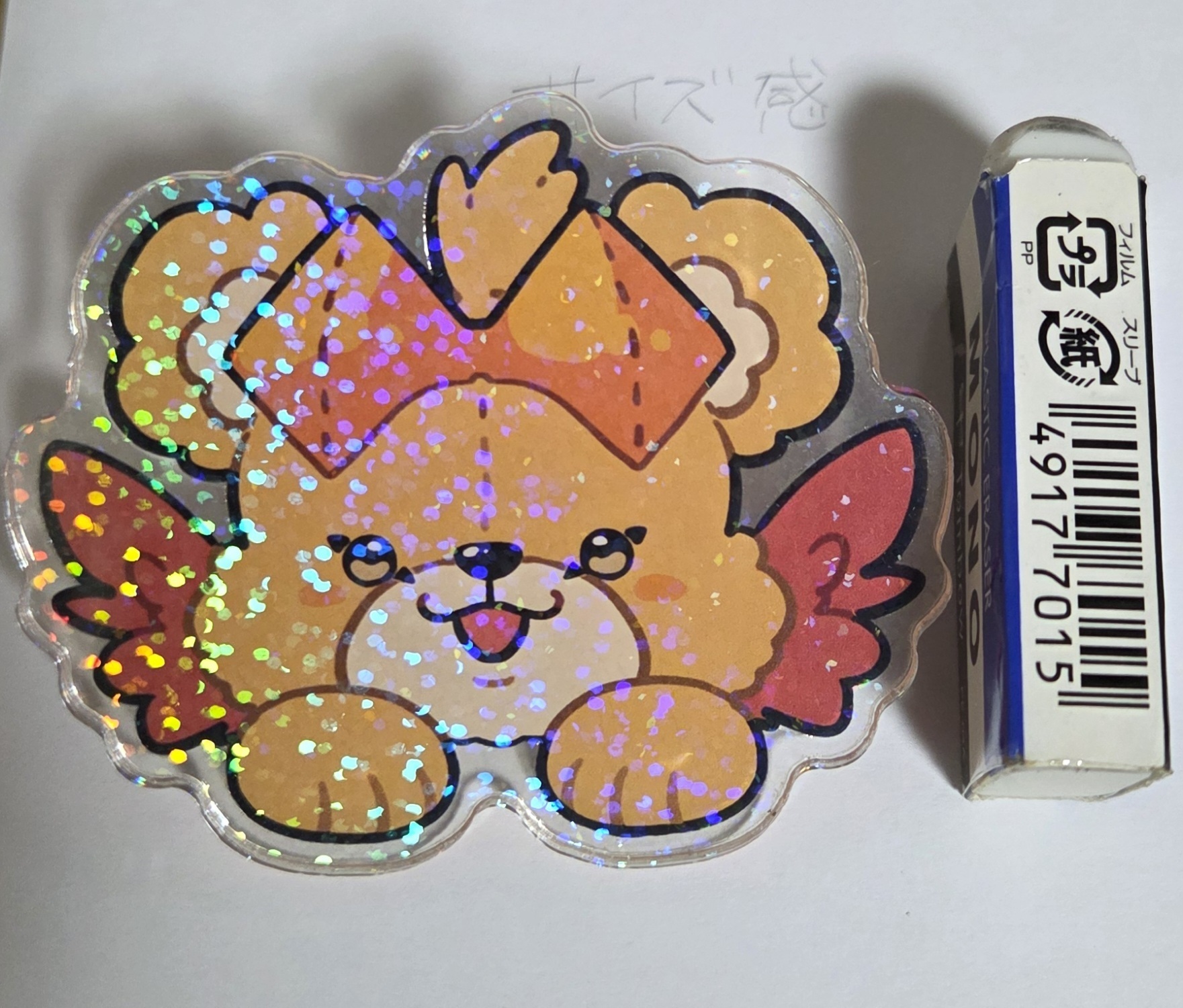 Photograph of the hair clip showing a glittery cartoon character beside a small box for scale.