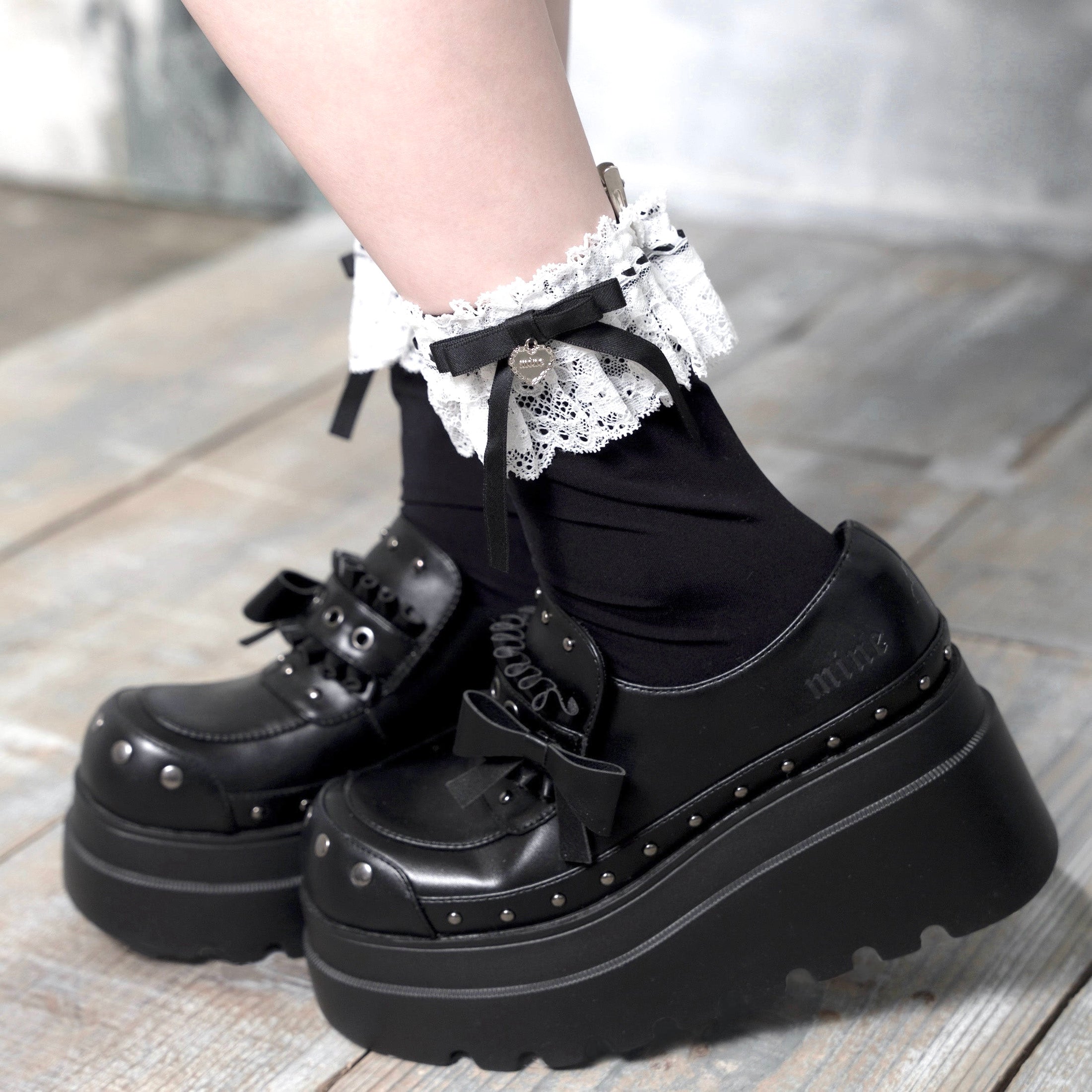 Close-up of a model's feet wearing the lolita crew socks with white lace cuffs and an attached charm.