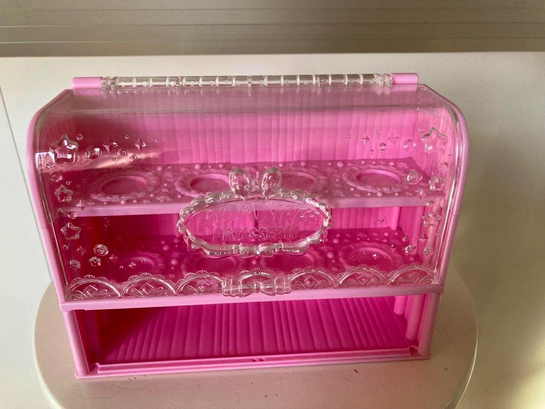 Pink plastic miniature sweets showcase cabinet toy with a clear hinged front cover and two display shelves with circular recesses.