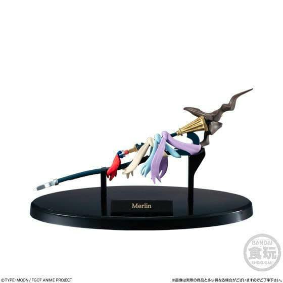 A miniature Merlin weapon prop figure displayed on a black oval base with a nameplate reading "Merlin".