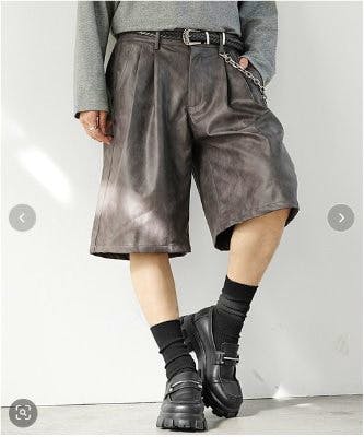 A model wearing men's vintage PU leather half shorts shown from waist to mid-calf with a belt and side chain detail.