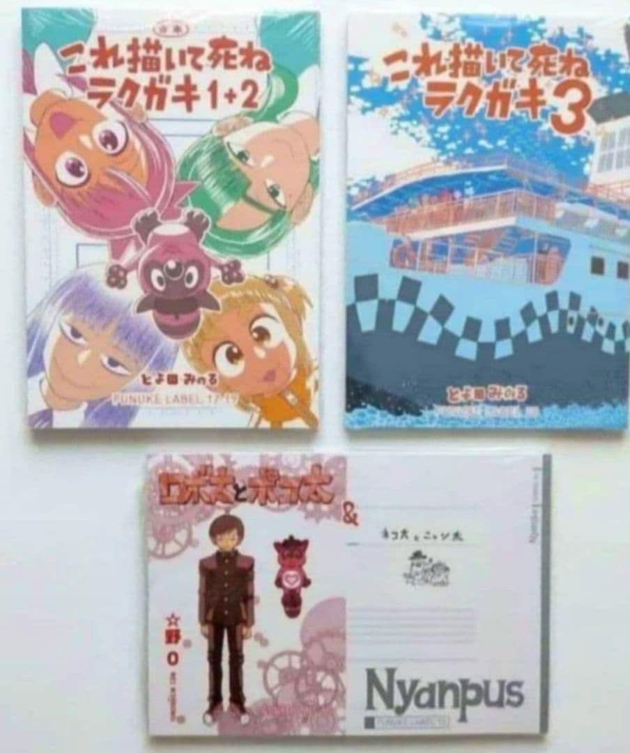Photo of three unopened doujinshi books laid out, showing covers for 'これ描いて死ね ラクガキ1+2', 'これ描いて死ね ラクガキ3', and a third book with 'Nyanpus' on the cover.