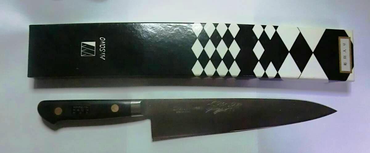 A Misono 210mm gyuto chef knife with a black handle and engraved blade shown next to its box.