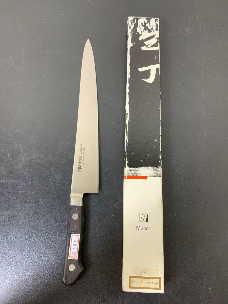 Misono 27cm chef knife with a dark wooden handle displayed next to its box on a dark surface.