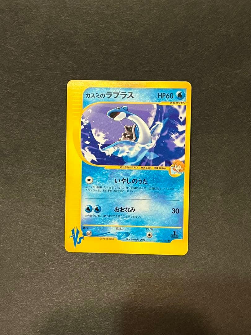 Photo of the front of the カスミのラプラス Pokémon trading card (VS 057/141) placed on a dark background.