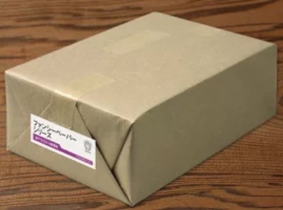 Wrapped pack of the listed printer paper in plain brown packaging with a small label, placed on a wooden surface.