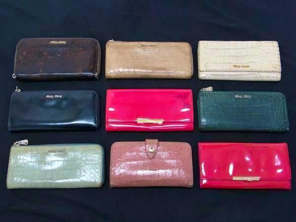 Nine miu miu wallets in various colors and finishes arranged on a black background.