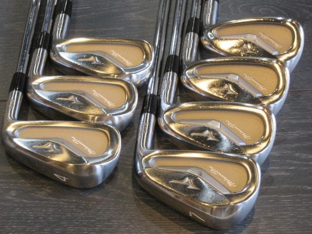 Seven Mizuno MP243 golf irons (4 through PW) arranged on a surface showing the club heads.