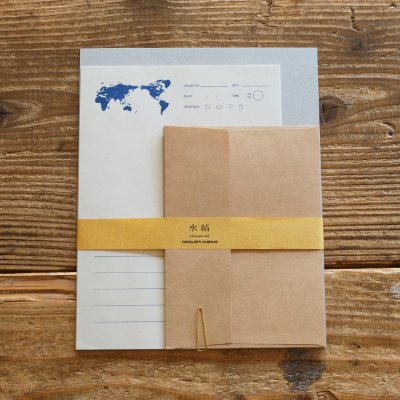 Top-down photo of the letter set showing world-map-printed writing paper, kraft envelopes, and a yellow band on a wooden surface.