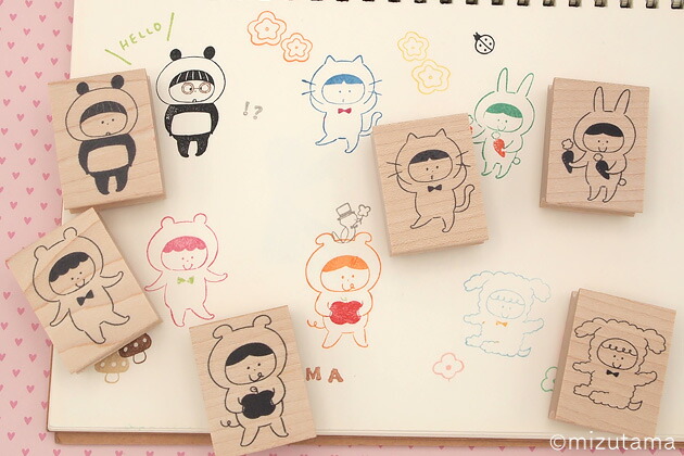 Several wooden mizutama character stamps arranged on an open sketchbook showing stamped cartoon impressions.