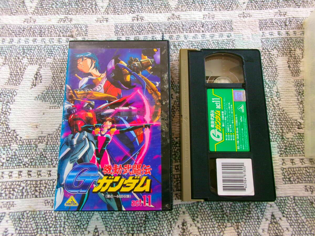 VHS tape and its illustrated case for the anime 機動武闘伝 Gガンダム act.11 displayed on a patterned surface.