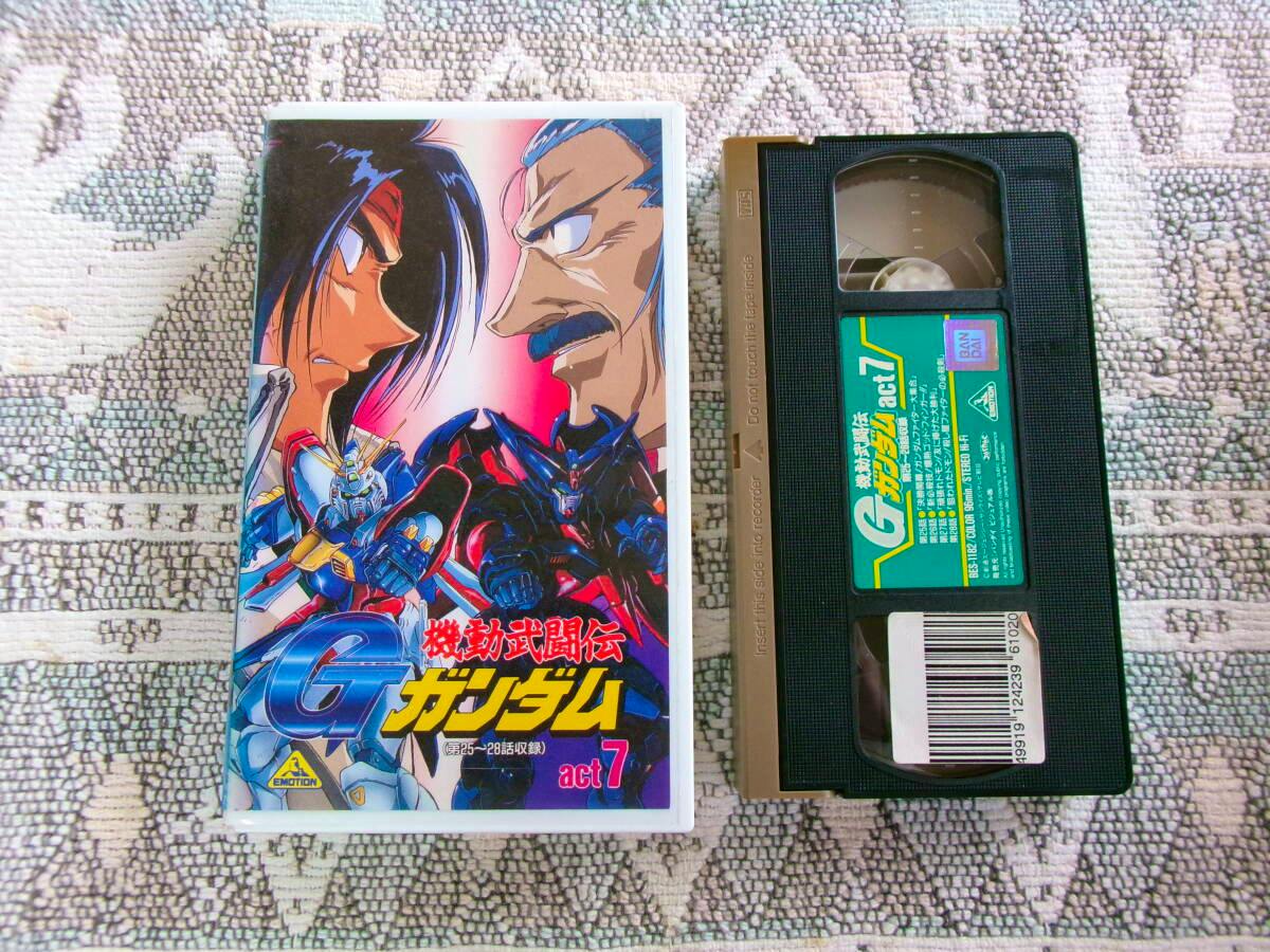 VHS tape and its illustrated front cover for 機動武闘伝 Ｇガンダム act.7 placed side by side on a patterned surface.