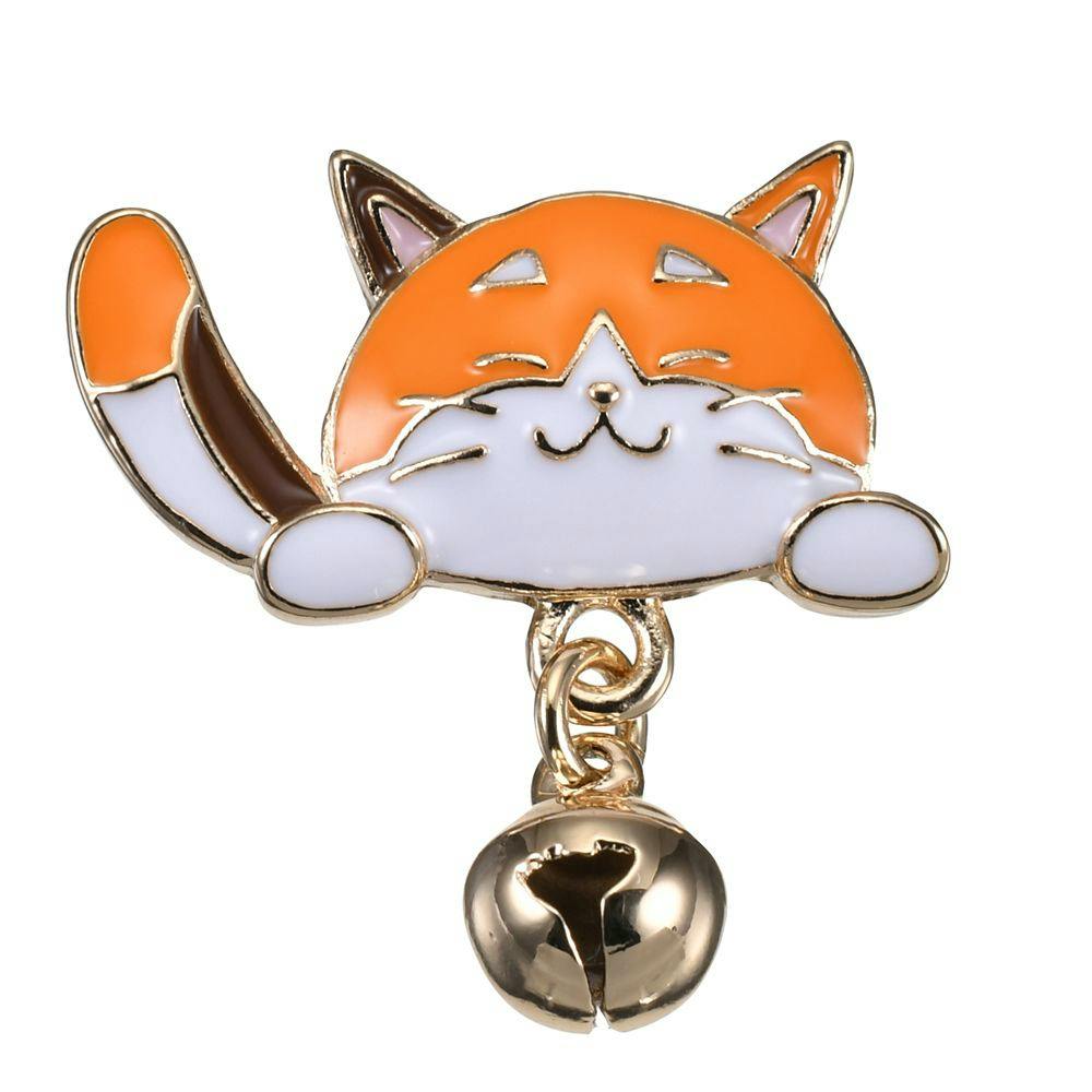Close-up of an orange-and-white cat enamel pin badge charm with a small dangling gold bell.