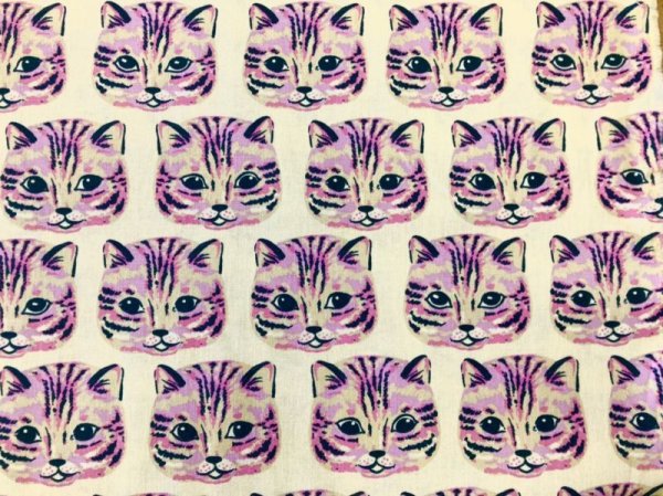 Off-white fabric showing a repeating pattern of stylized purple cat faces.