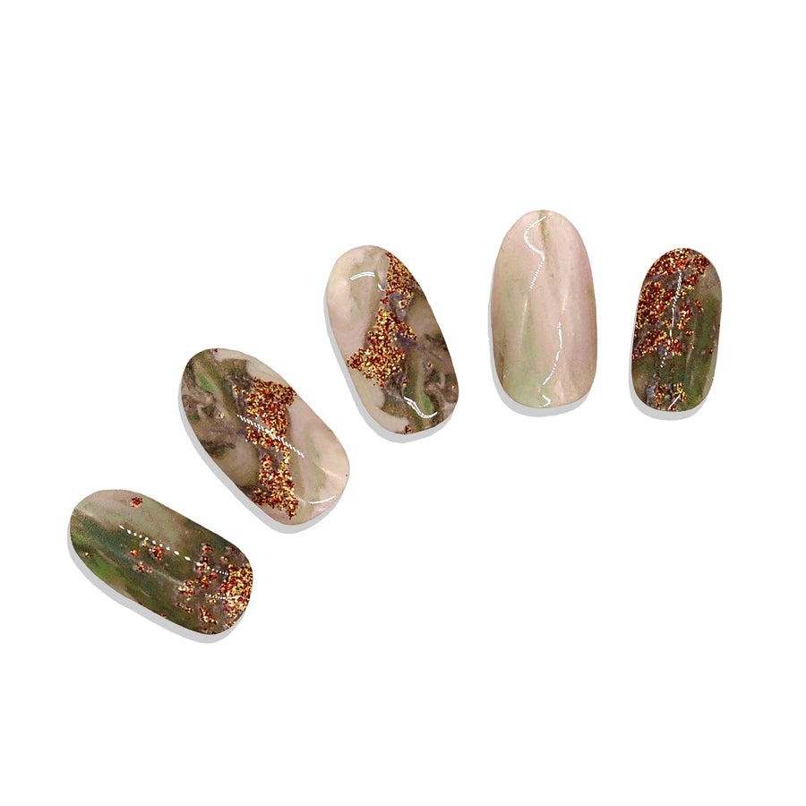 Five nail stickers with green and pale peach marble design and glitter accents on a white background.