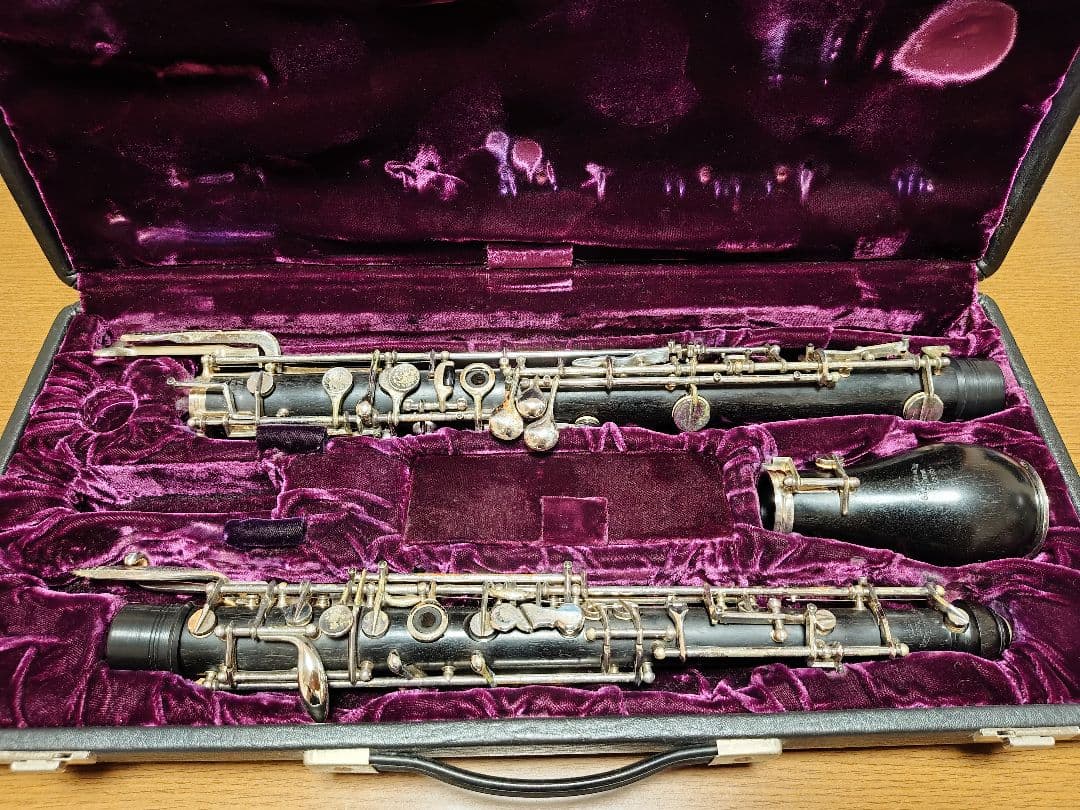 An English horn (disassembled into body and bell) placed in an open hard case with purple velvet lining.