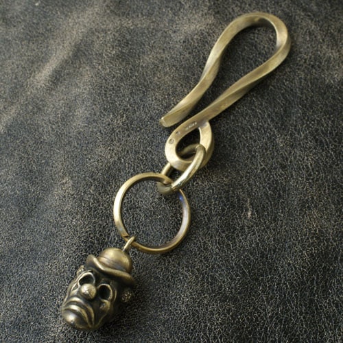 Metal PIERROT keyholder featuring a sculpted Pierrot head charm attached to a large clip and split ring on a dark leather background.