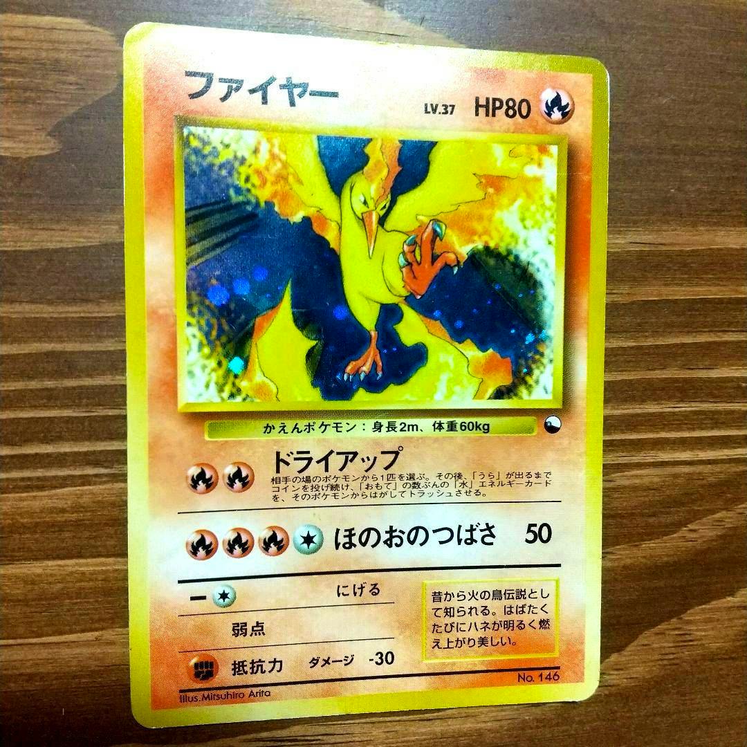 Front of a Japanese ファイヤー trading card showing the artwork, attack text, and HP80 photographed on a wooden surface.