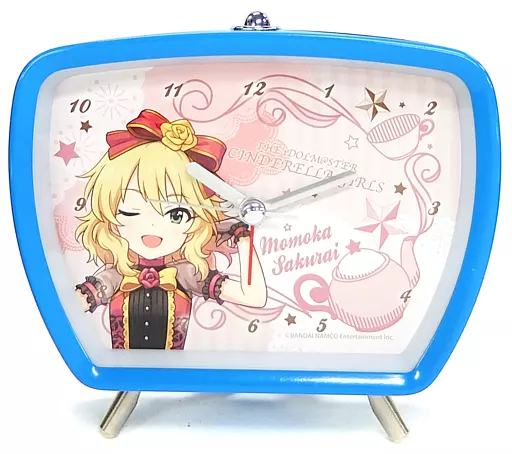 Blue-framed tabletop alarm clock showing a printed illustration of Momoka Sakurai from The Idolmaster Cinderella Girls with visible clock face and hands.