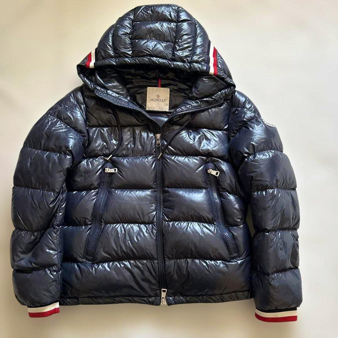 Navy Moncler men's down jacket laid flat showing front, hood, and zippered pockets.