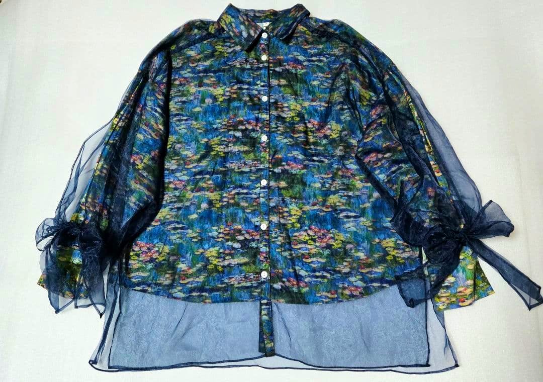 Front view of a women's chiffon-layered blouse with Monet water-lily print, button-front and sheer long sleeves tied with bows, laid flat.