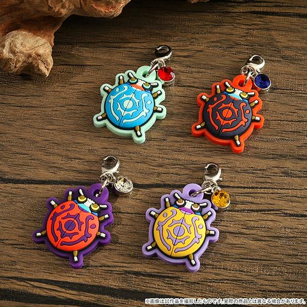 Four rubber Mononoke keychain charms with front designs in different colors arranged on a wooden surface.