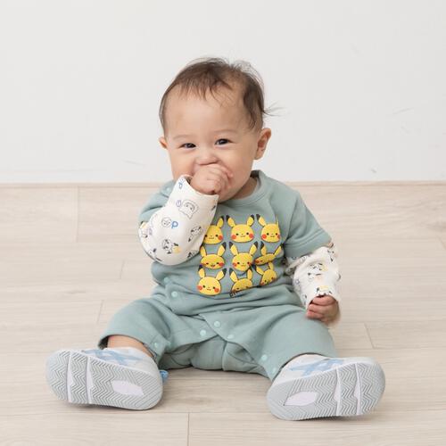 Infant model seated on a light floor wearing the green long-sleeve layered-style romper with Pikachu prints.