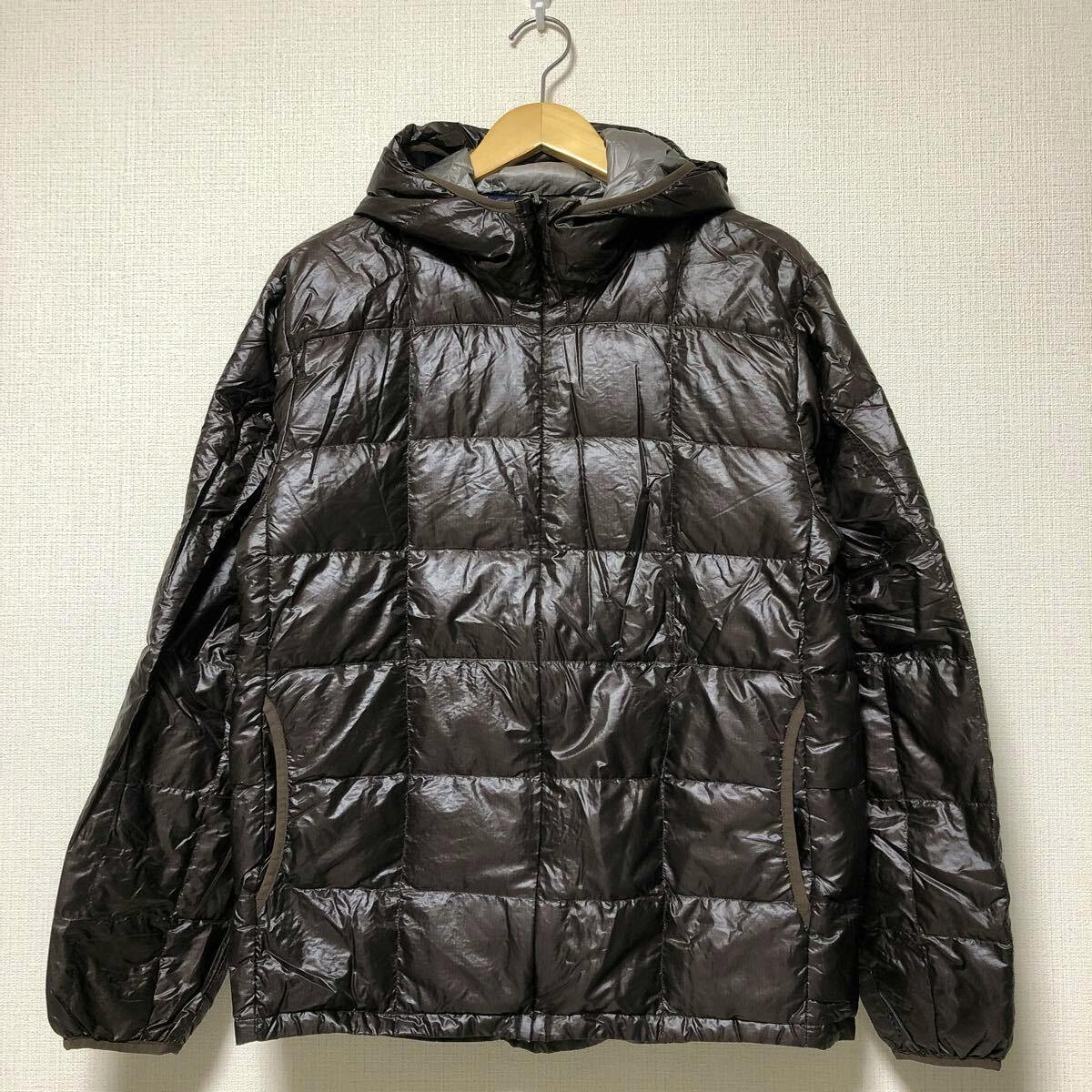 Mont‑bell men's brown nylon U.L. down hooded jacket hanging on a hanger against a wall.