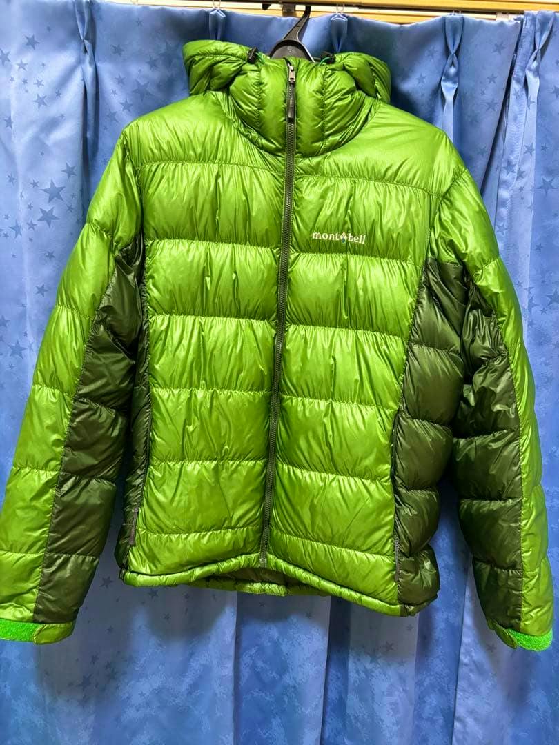 Front view of a green Montbell down jacket with hood hanging on a hanger, logo visible on the chest.