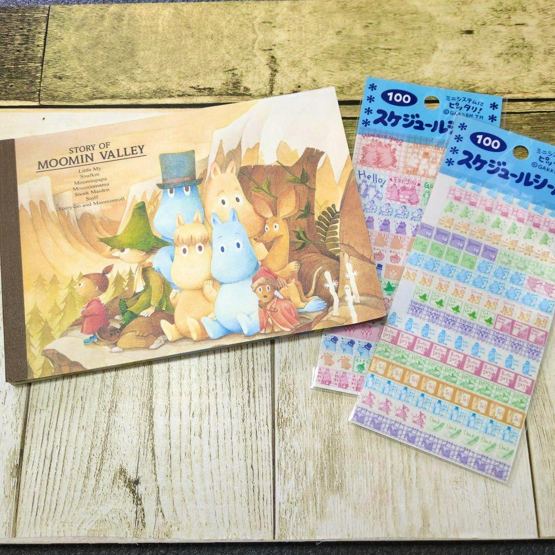 A Moomin-themed memo pad displayed next to two sheets of colorful schedule stickers on a wooden surface.