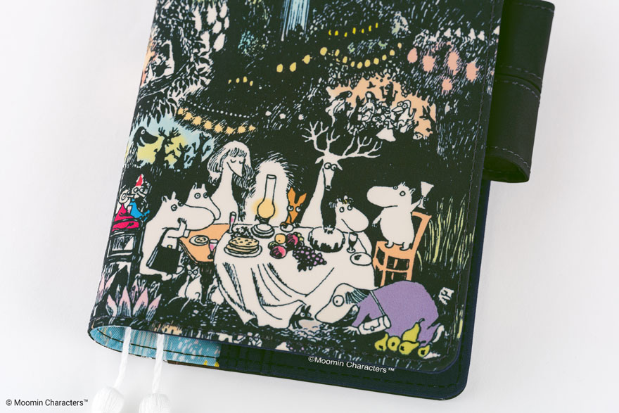 A Moomin A6 diary front cover showing the 'Night of the Big Party' illustration of Moomin characters seated around a table.