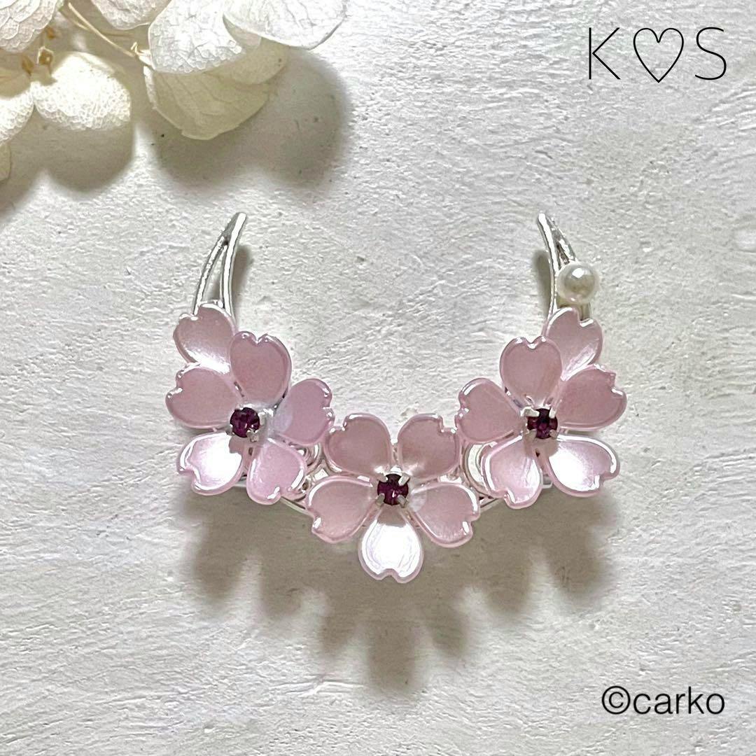 Obidome with three pink cherry blossom flowers with light-amethyst centers and a small pearl on a textured white background.