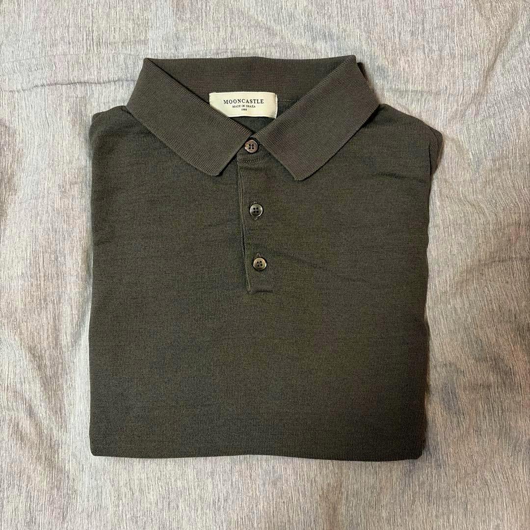 Folded charcoal Mooncastle knit polo shirt showing the collar, three-button placket, and brand label.