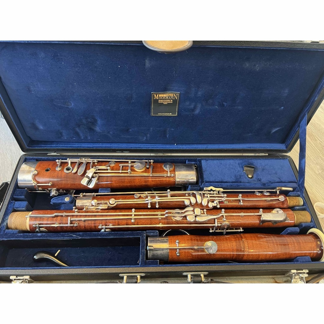 Disassembled Moosmann 447E bassoon placed inside its open carrying case showing the body sections and keywork.
