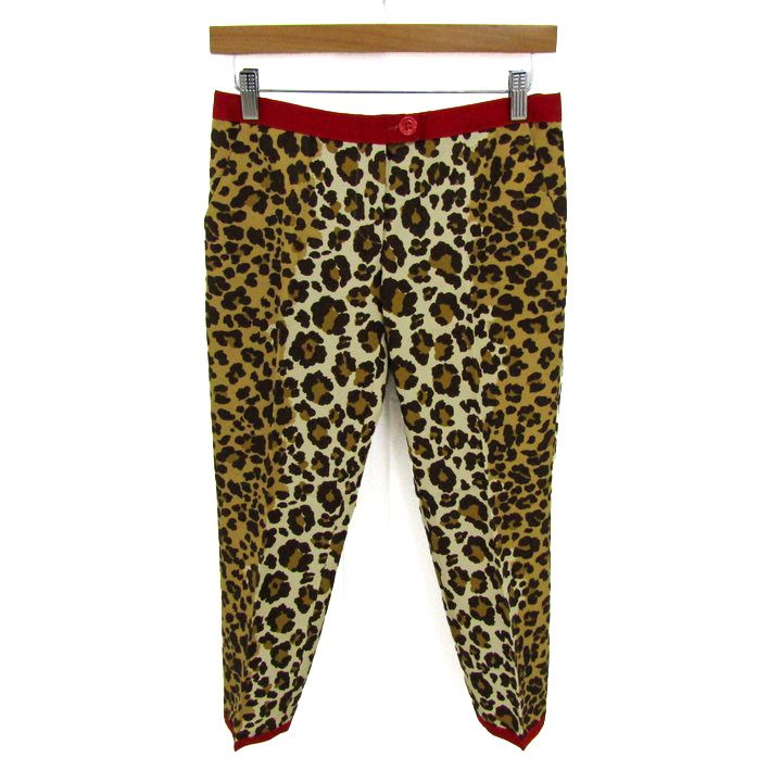 Beige leopard-print women’s tapered pants with a red waistband and red ankle trim hanging on a wooden hanger against a white background.