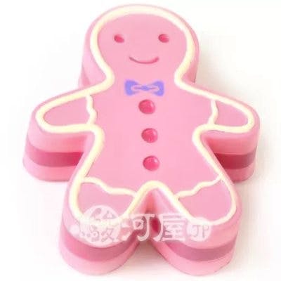 Pink gingerbread-man shaped toy with white trim, a purple bow design, and three button details on a white background.