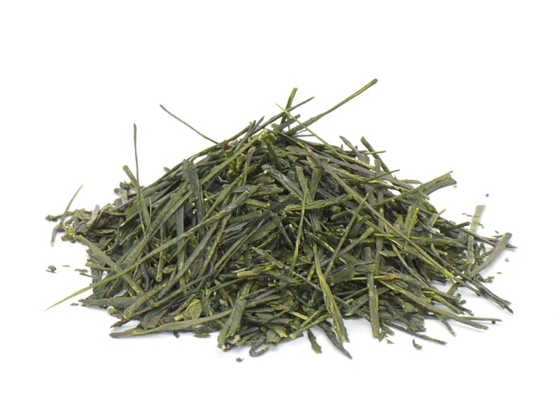 Loose green tea leaves (sencha) piled on a white background.