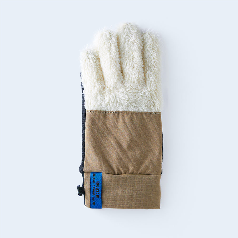 Flat-lay photo of a women's white and beige fleece glove with a blue label on a light background.