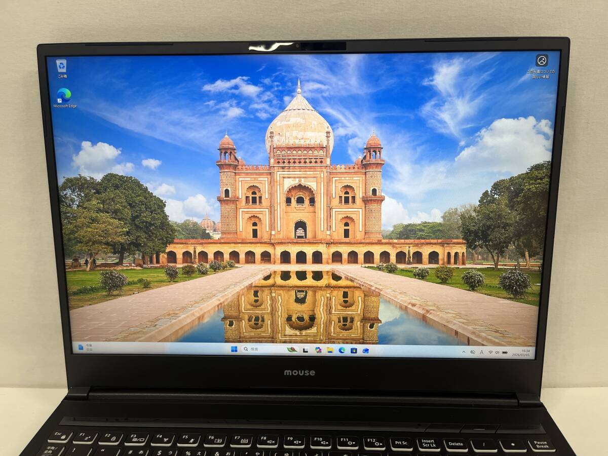 Front view of the Mouse G-Tune H6-I9G80BK-A laptop with the display on showing a scenic desktop wallpaper and the keyboard visible.