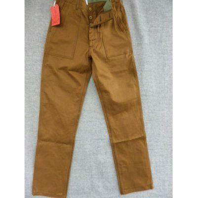 Brown cotton women's pants laid flat on a gray background, showing front patch pockets, button fly, and a red tag.