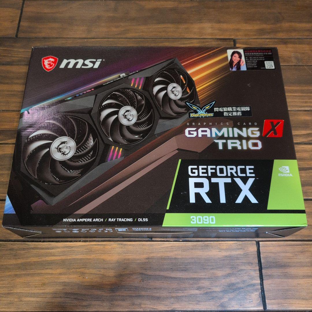 Box for an MSI GeForce RTX 3090 GAMING X TRIO graphics card shown on a wooden surface.