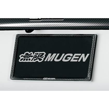 A Mugen carbon fiber license plate garnish/frame mounted on a vehicle rear surrounding a license plate.