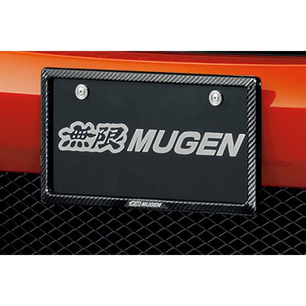 A carbon fiber license plate garnish installed on a car rear bumper around a MUGEN-branded license plate.