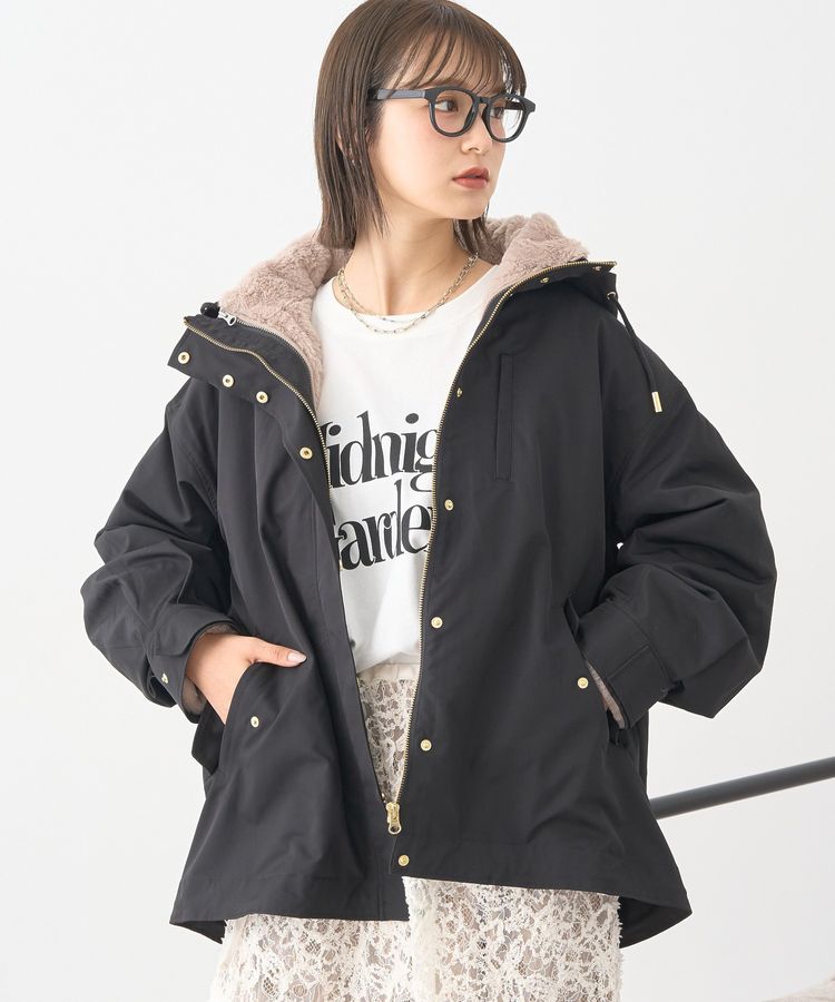 A model wearing a black multiway mountain parka with a light-colored plush hood lining and hands in pockets.