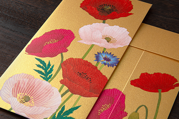 Close-up photo of a gold multipurpose envelope printed with red, pink, and white poppy flowers.